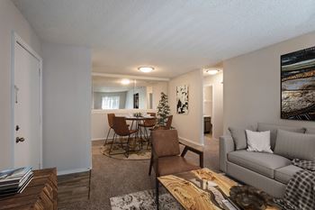 The living room and dining room of an apartment with a couch and chairs